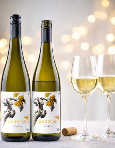 Dos botellas de vino blanco sin alcohol GOODVINES Riesling junto a dos copas.
