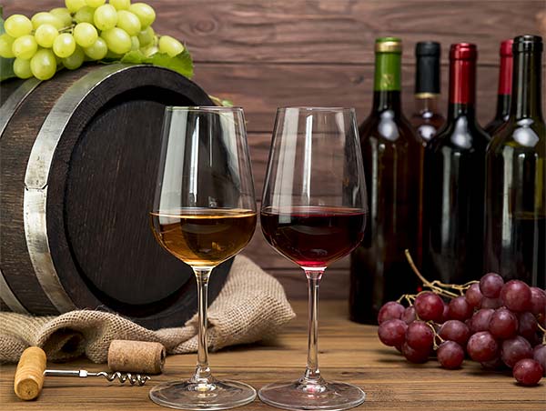 Copas de vino junto a un barril y uvas.